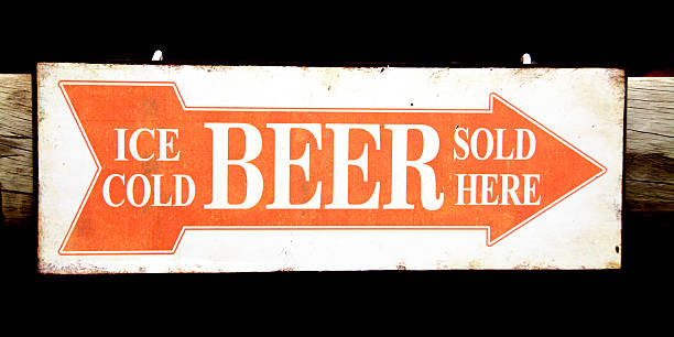 Ice Cold Beer Sold Here Closeup of an Orange and White Sign indicating the Direction to the Bar - Ice Cold Beer Sold Here rusty pole stock pictures, royalty-free photos & images