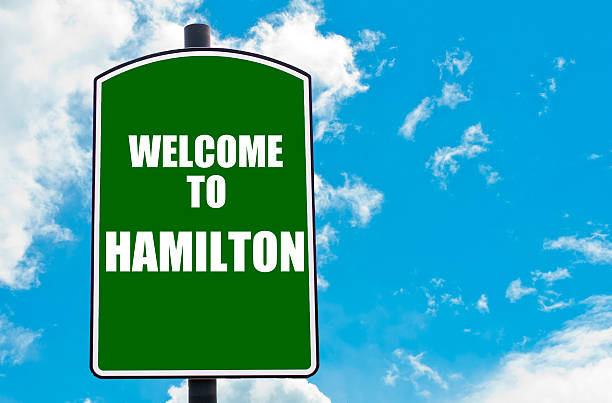Welcome to HAMILTON Green road sign with greeting message Welcome to HAMILTON isolated over clear blue sky background with available copy space. Travel destination concept image scotland border sign stock pictures, royalty-free photos & images