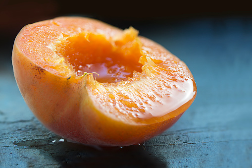 halved apricot, ripe and juicy on blue wood, closeup with selected focus and narrow depth of field