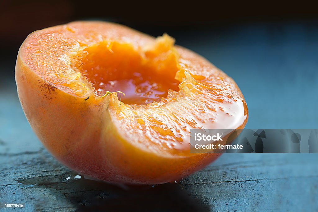 Para metade de damasco maduro e suculento, em azul madeira, detalhe - Foto de stock de Pêssego royalty-free