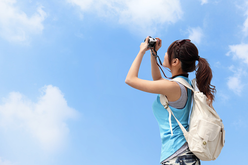 Happy woman traveler photo by camera with blue sky