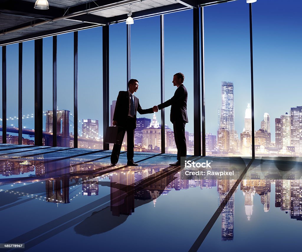 Multi-Ethnic Businessmen Shaking Hands Indoors With City As A Background Business Stock Photo