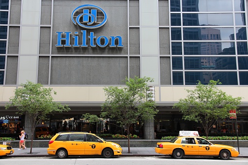 New York, United States - July 4, 2013: People walk past Hilton hotel at 6th Avenue in New York. Hilton is  the 38th largest private company in the United States according to Forbes.