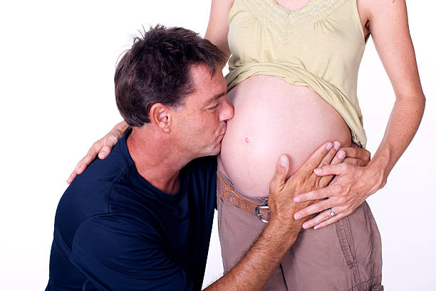 mann küssen schwanger frau ist nackt bauch - two parent family naked men couple stock-fotos und bilder