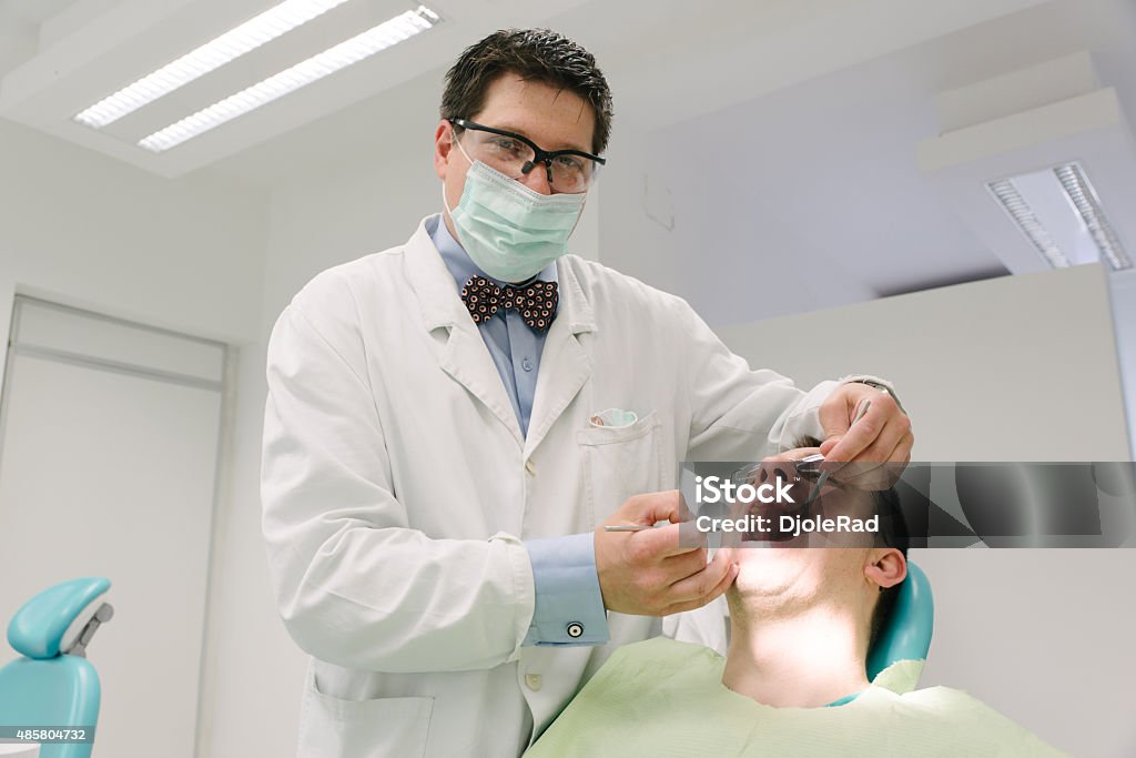 Dentist examining his patient A dentist checks up on a regular patients teeth health. 2015 Stock Photo