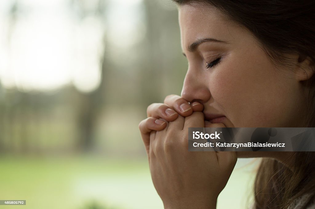 Depressed young woman crying Horizontal view of depressed young woman crying Praying Stock Photo