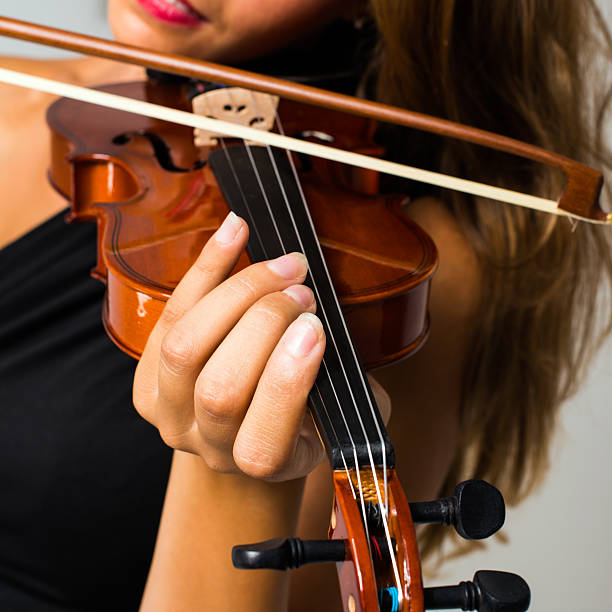 istock Beautiful young woman playing violin closeup 485807864