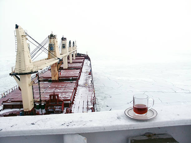 Massive different ship vessels trapped in ice tries to break and leave the bay between the glaciers, icebreaker and carrier vessel, winter blue sky