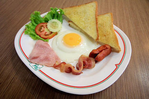 istock breakfast with fried eggs, bacon, sausages and fresh salad 485821834