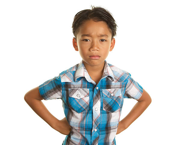 A handsome Filipino Boy on a white background.  He has his hands on his hips and is looking at the camera with a very sad unhappy expression.