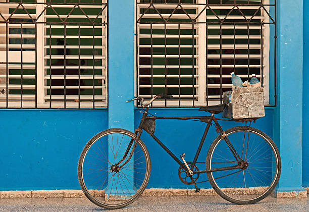 istock Old bicycle leaning against barred,shuttered windows and blue wall 485823594