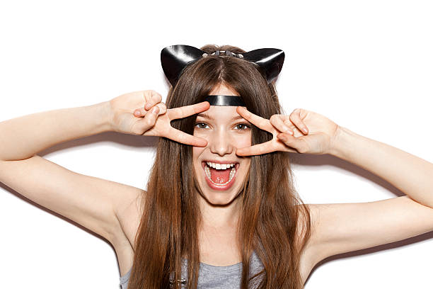 Funny girl represents as small cat.  Woman  with bright makeup hairstyle of girl with leather cat ears having fun. On white background not isolated