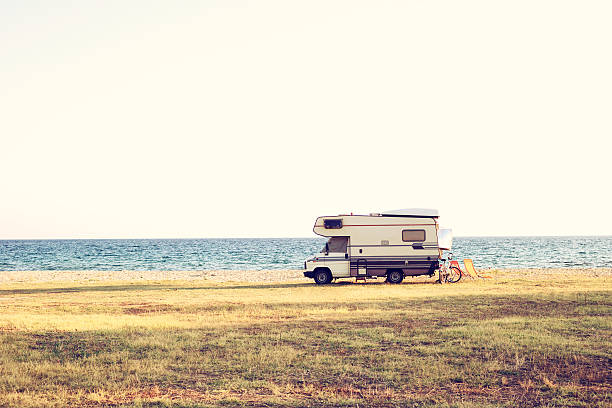Summer day RV vacation. A vintage shoot with a caravan car near the Mediterranean sea in a beautiful summer day. Copy space also. camper trailer photos stock pictures, royalty-free photos & images