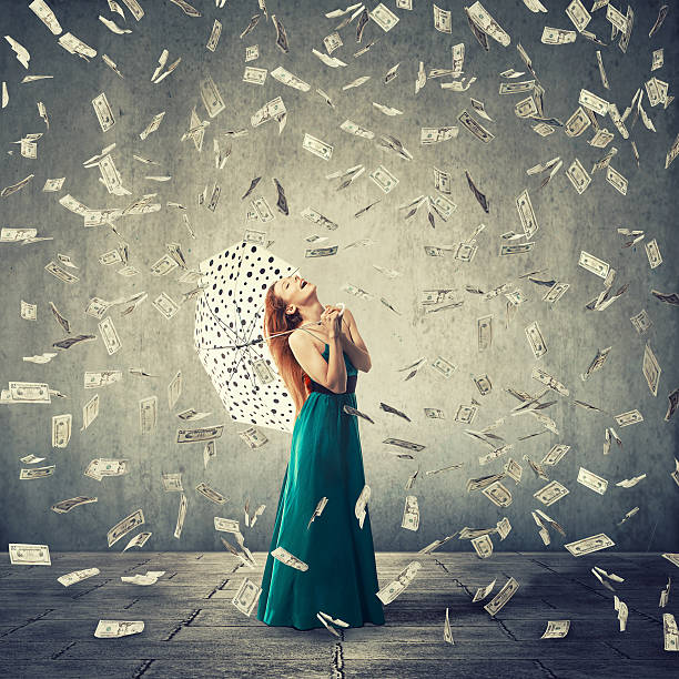 Happy woman with umbrella under a money rain Excited young woman with umbrella under a money rain isolated on grey wall background. Positive emotions financial success luck good economy concept frequency photos stock pictures, royalty-free photos & images