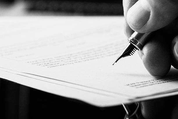 Fountain Pen Signature. A hand holding a fountain pen and about to sign a letter. Styling and small amount of grain applied. treaty stock pictures, royalty-free photos & images