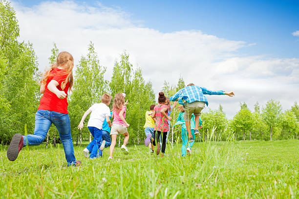 istock View from behind of kids running through  field 485834192