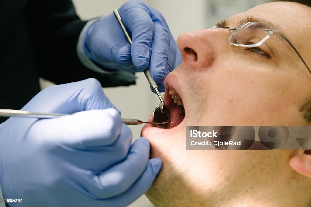 Closeup inspection of patients mouth. Dentist performs a thorough examination of the patient's mouth health. 2015 Stock Photo