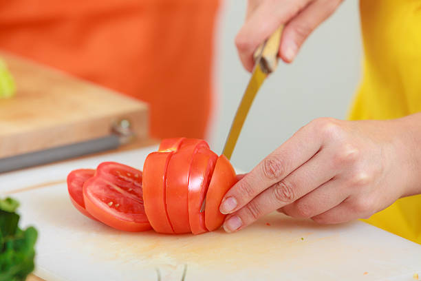 istock Woman preparing vegetables salad slicing tomato 485843250