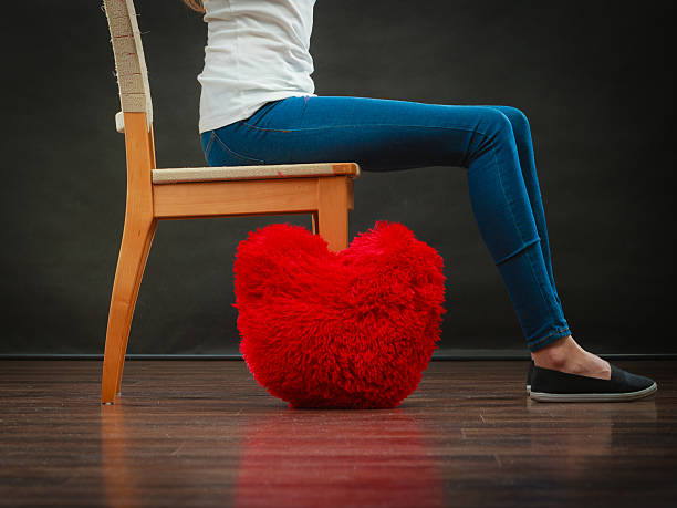 istock Woman legs with red heart pillow on floor 485844954