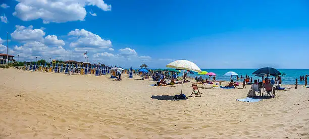 Beautiful scene of typical vacation beach with beach chairs and sun shades on a sunny day at Lido di Metaponto, Basilicata, Italy