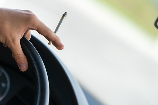 Close-up of a men driving and smoking joint