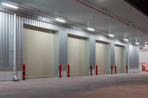 Exterior of factory with shutter door, night time.