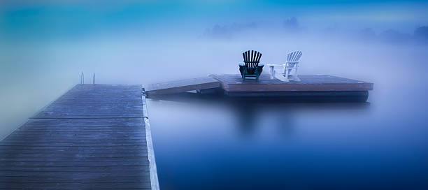 Muskoka Chairs in Cottage Country Photo was taken in the pre-dawn period on a foggy Autumn morning, in Huntsville, Ontario, Canada, by a lakeside dock.    huntsville ontario stock pictures, royalty-free photos & images