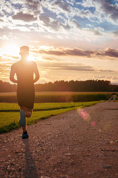istock Back view of man running on the road at sunset 485852378