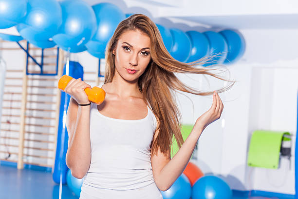 Young pretty woman holding weights (dumbbell). gym hall. stock photo