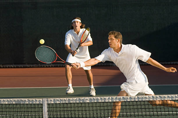 tenis gracz uderzając piłkę podwójne partnerem, stojąc w tył - doubles zdjęcia i obrazy z banku zdjęć