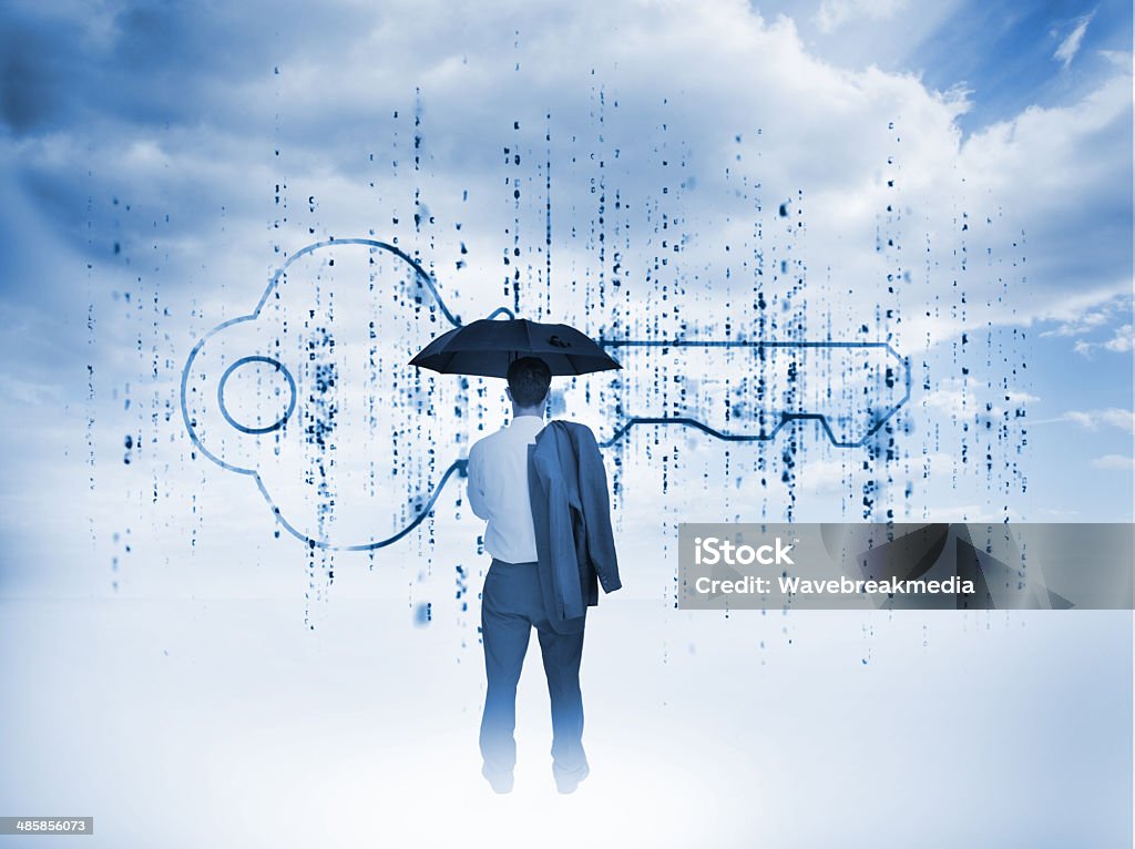 Businessman with an umbrella looking at a giant key Businessman with an umbrella looking at a giant key with blue sky on the background Horizontal Stock Photo