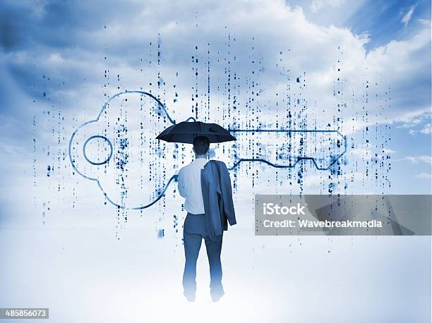 Businessman With An Umbrella Looking At A Giant Key Stock Photo - Download Image Now