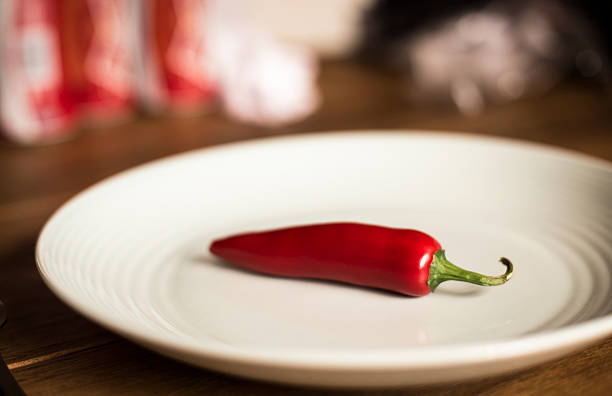 Single large Chilli pepper on a pale blue plate. stock photo