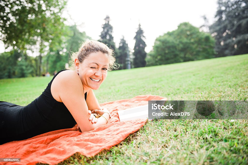 Mujer leyendo un libro en el parque - Foto de stock de Guiñar el ojo libre de derechos