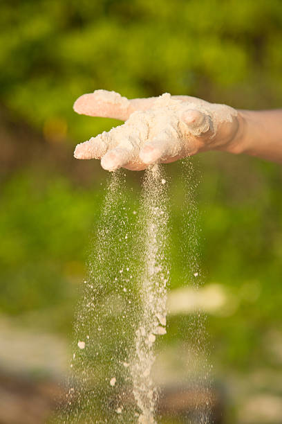 istock Hand, with falling sand outdoor, green plant background 485864344