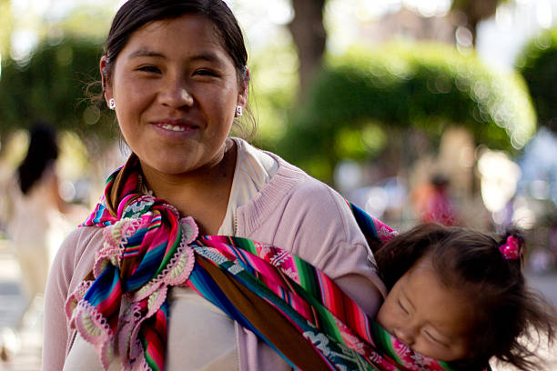 Sucre, Bolivia - January 17, 2012: A bolivian mom carries her child on her back, tied up with a colorful traditional piece of fabric. January 17, 2012 in Sucre, Bolivia.