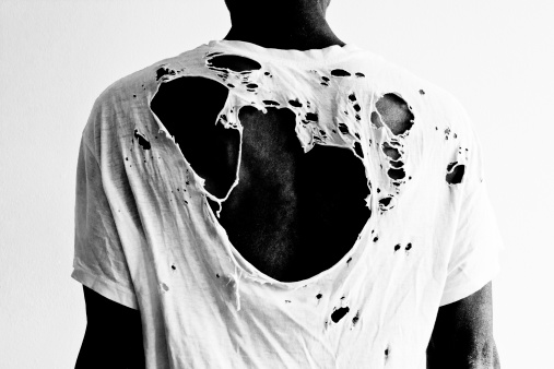 Back of a black man wearing a naturally distressed ripped white cotton t-shirt full of holes