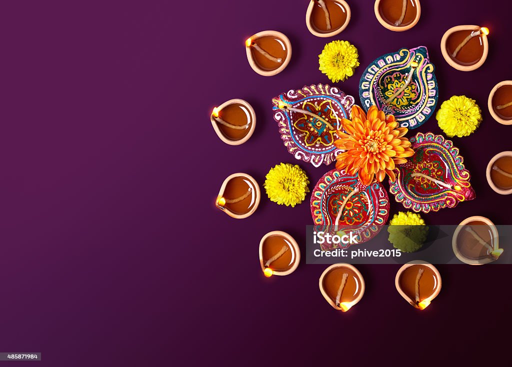 Diwali Oil Lamp Colorful clay diya lamps with flowers on purple background Diwali Stock Photo