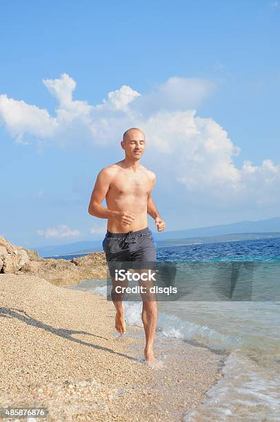 Young Man Running Jogging On Beach Stock Photo - Download Image Now - 2015, Active Lifestyle, Activity