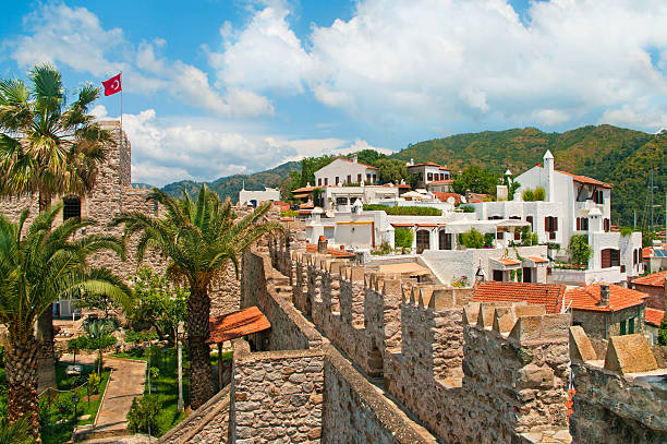 view of castle walls and old town view of Marmaris castle with Turkish flag and white houses in old town with green mountains at background on sunny day against blue sky, Marmaris, Turkey marmaris stock pictures, royalty-free photos & images