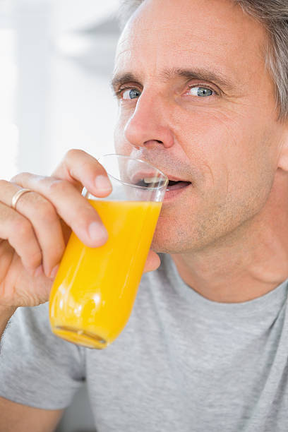 istock Cheerful man drinking orange juice in kitchen 485878079