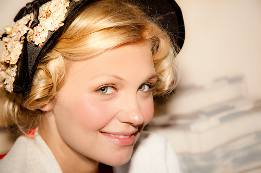 Beautiful blonde Victorian-dressed girl smiles for camera.  This southern belle wears a retro bonnet with curls around her face. 