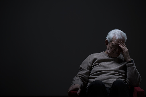 Despairing senior man on a dark background