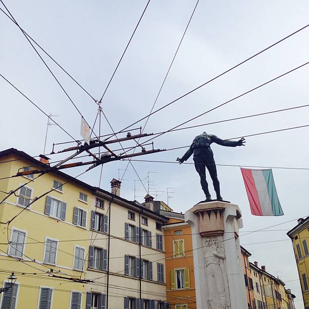 Parma, Italy - April 18, 2014: Parma is one of the few Italian towns where trolley buses can run because the electrical subsystem of the suspended cables is in place. An important crossroad is situated near the monument to Filippo Corridoni, in Via Massimo D'Azeglio. 