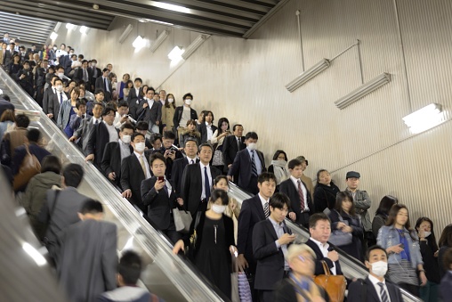 Tokyo, Japan - April 16, 2014: Crowds of commuters standing on escalators at Nagatacho Station.