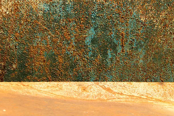 Two metal rusty metal surfaces of derelict water tanks. One horizontal the other vertical behind giving the illusion of one surface divided into two different colour fields, one covered in blistered and peeling blue paint, the other a rusty orange hue. Horizontal line riding image just below the third/ two thirds line.