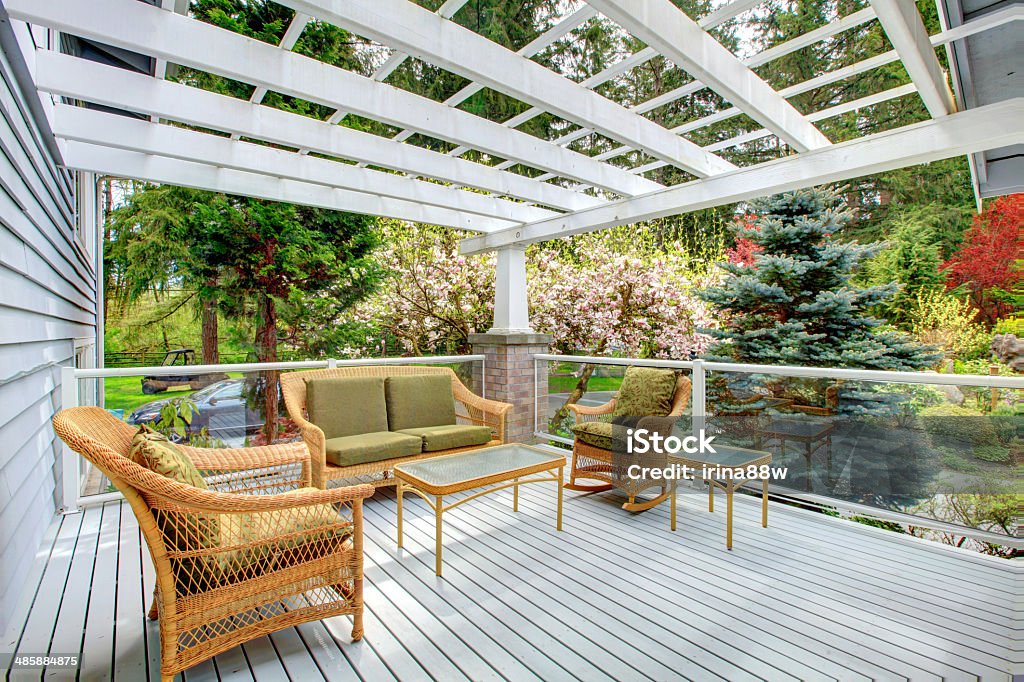 Cozy countryside house walkout deck Cosy covered walkout deck with wicker and rocking chairs, settee, coffee table. Screened deck overlooking beautiful flourishing garden Architecture Stock Photo