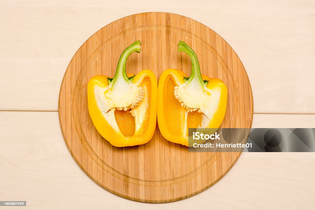 Yellow bellpepper in two halves The two halves of a yellow bellpepper photographed on a wooden plate 2015 Stock Photo