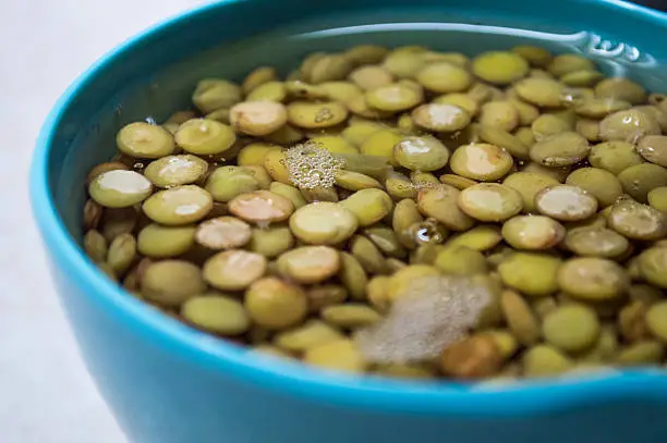 A measured amount of lentils soaking in some water in a bowl - the proper procedure before cooking dried lentils.