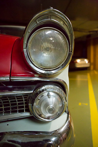 Detail of bumper and head light of an American vintage car taken in a garage in Barcelona.